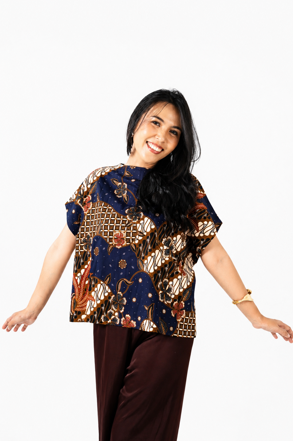 Woman wearing a patterned top and brown pants on a white background