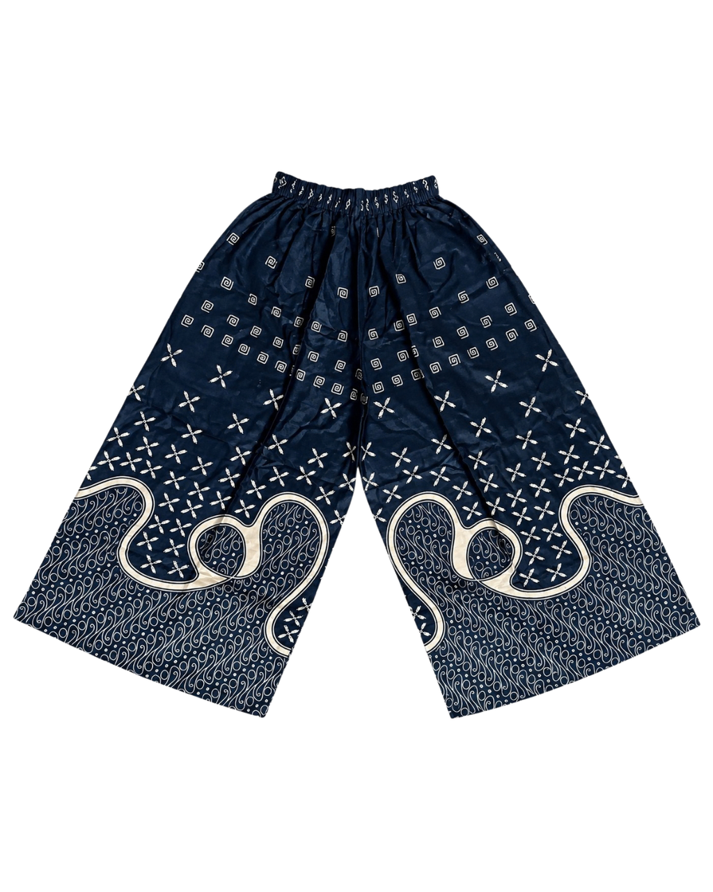 A pair of loose, wide-leg shorts in navy blue with white indigo-dyed bandhani patterns, geometric dots, and large abstract swirl motifs near the lower legs, displayed flat against a white background.