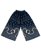A pair of loose, wide-leg shorts in navy blue with white indigo-dyed bandhani patterns, geometric dots, and large abstract swirl motifs near the lower legs, displayed flat against a white background.