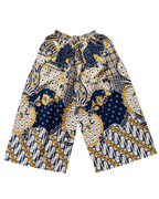 A pair of wide-leg shorts featuring a vibrant batik-style pattern in navy blue, yellow, and cream, displayed flat against a solid white background.