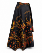 A black wrap-style midi skirt with a wide waistband and tie, featuring a vibrant golden-orange and red phoenix and floral pattern, shown against a plain white background.