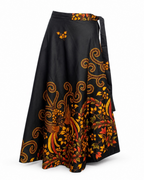 A black wrap-style midi skirt with a tie waist and a bold orange, yellow, and red floral and scroll pattern, shown against a plain white background.