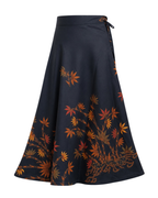 A navy blue A-line wrap skirt featuring a detailed print of orange, red, and brown maple leaves and branches, with a matching navy waistband and side tie closure.