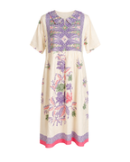 A short-sleeved midi dress with a cream base and a colorful botanical and geometric print in purple, pink, and green, featuring a decorative yoke and a pink hem.