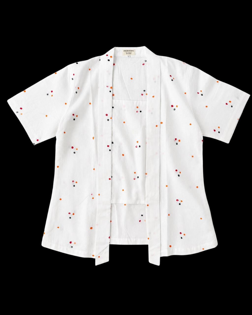 A white short-sleeve button-front shirt with a small scattered embroidered pattern in red, orange, and black, displayed flat against a solid black background.