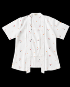 A white short-sleeve button-front shirt with a small scattered embroidered pattern in red, orange, and black, displayed flat against a solid black background.