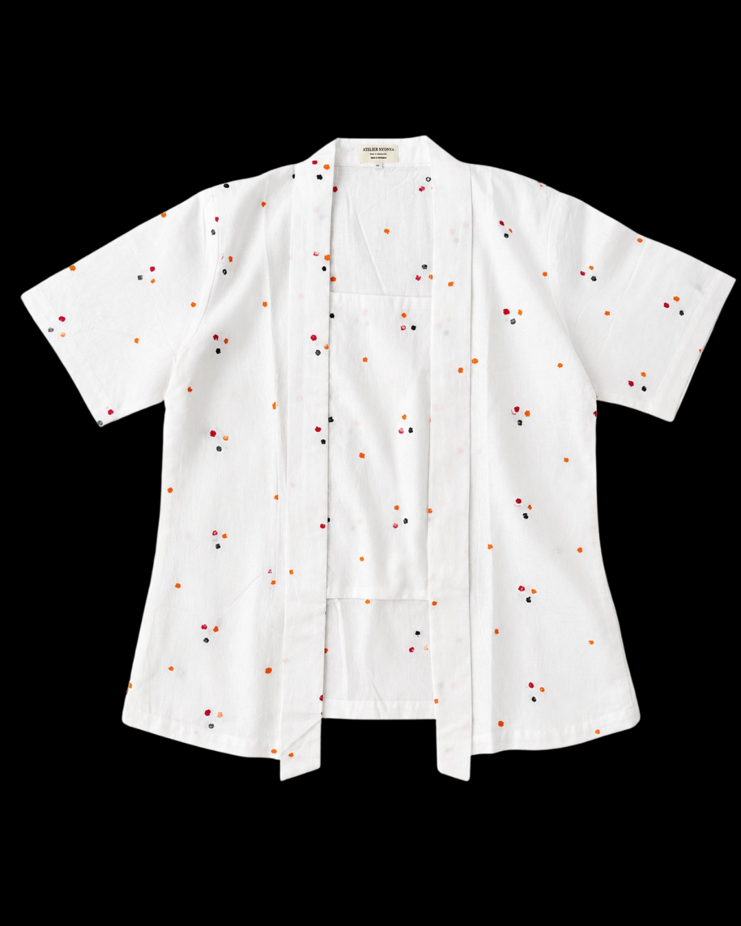 A white short-sleeve button-front shirt with a small scattered embroidered pattern in red, orange, and black, displayed flat against a solid black background.