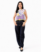 Woman wearing a floral sleeveless top and dark jeans on a white background