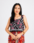 Woman wearing a sleeveless floral top and colorful pants on a white background