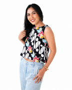 Woman wearing a black sleeveless top with colorful floral patterns on a white background