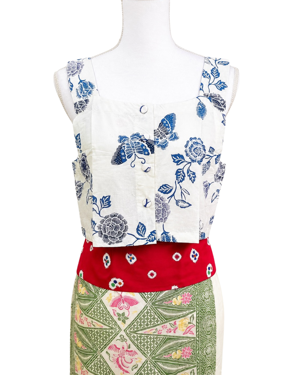 Mannequin wearing a floral-patterned top with a red skirt and green patterned bottom on a white background