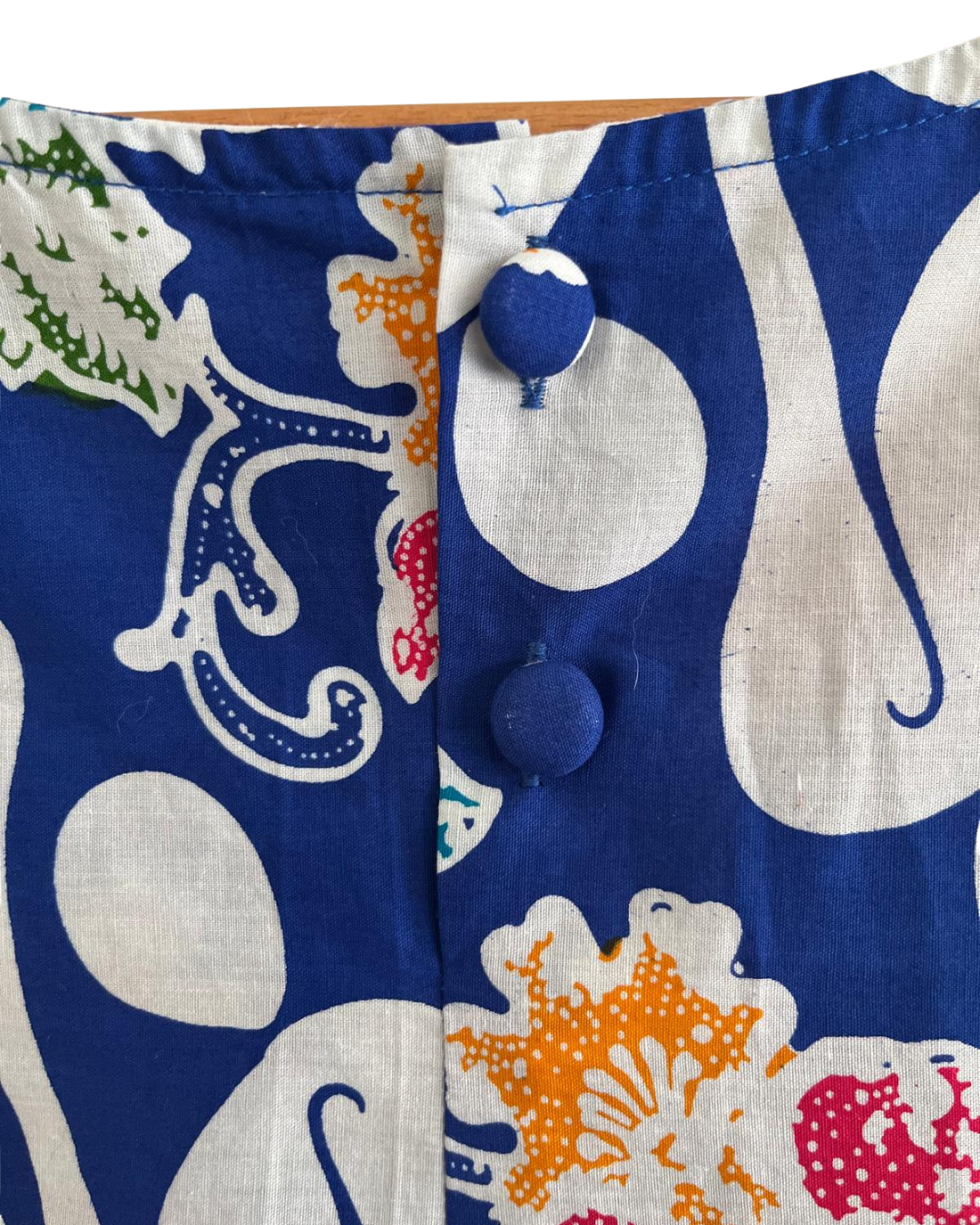 Close-up of a fabric with a colorful pattern featuring blue, white, orange, and green elements.