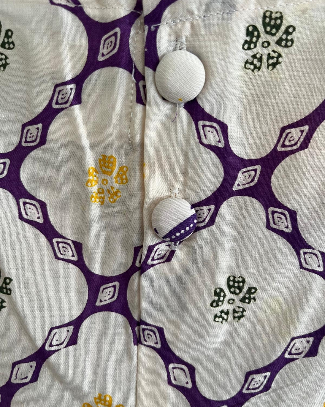Close-up of a fabric with purple and white geometric pattern and buttons.