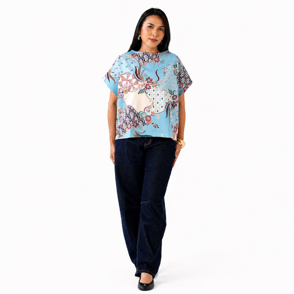 Woman wearing a colorful patterned top and dark pants on a white background